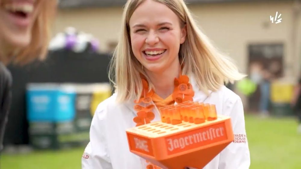 A smiling girl holding a box at an event – a still from a promo video